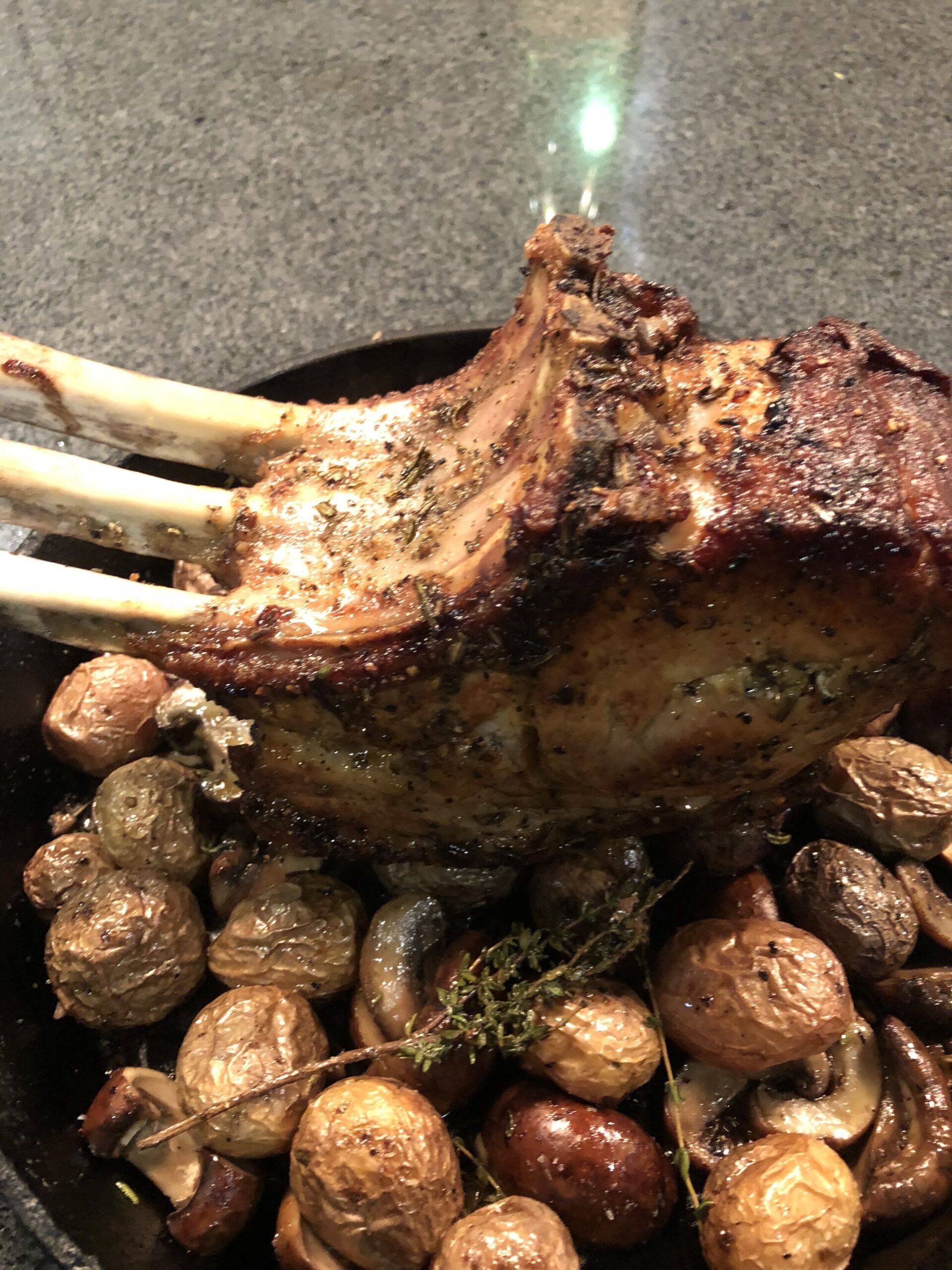 Roasted rack of lamb served on a bed of golden baby potatoes and mushrooms, garnished with fresh thyme, showcasing a flavorful and appetizing dish perfect for gourmet dining.