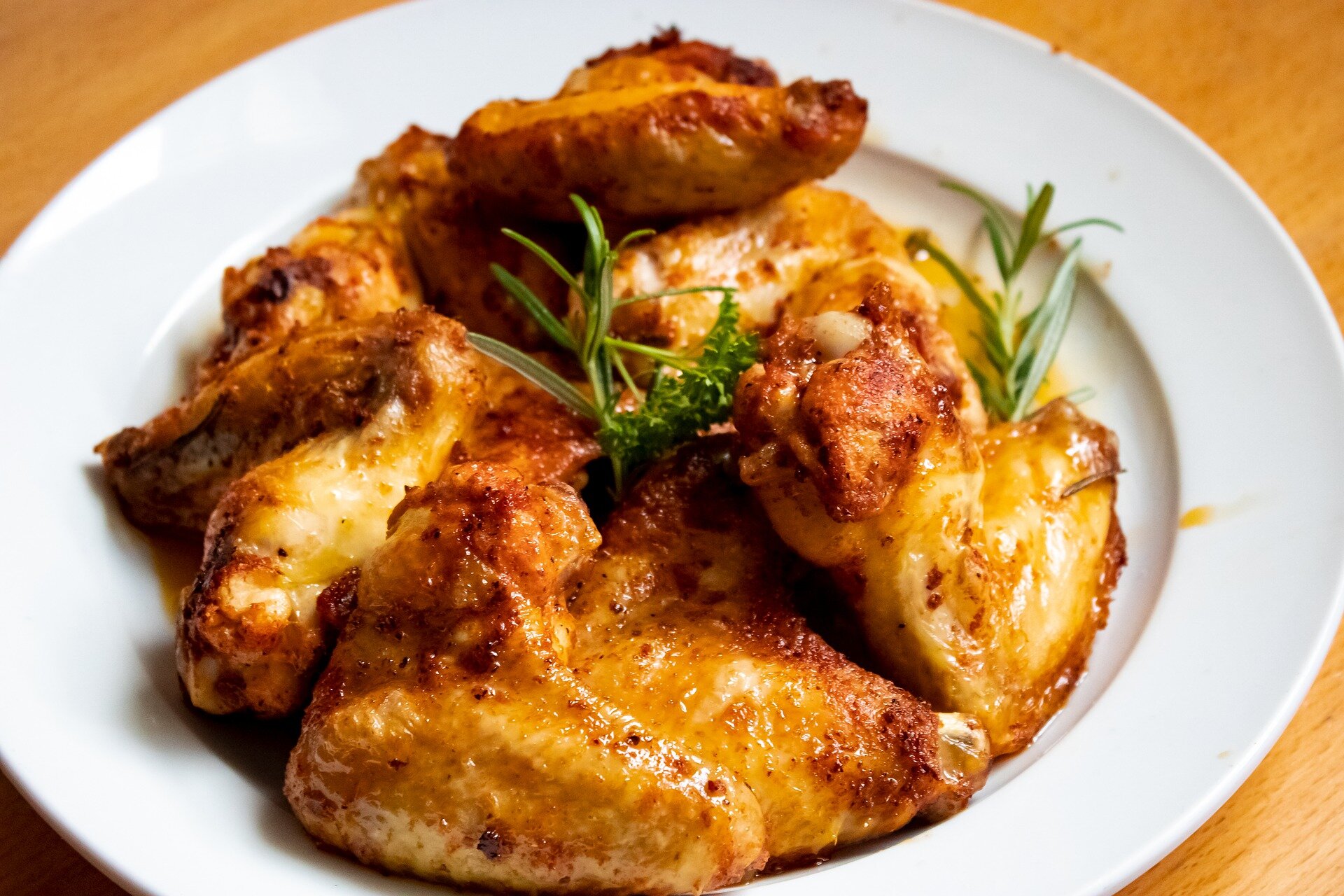 Golden-brown crispy chicken wings garnished with fresh herbs on a white plate, showcasing a delicious appetizer or main dish perfect for gatherings or game day.